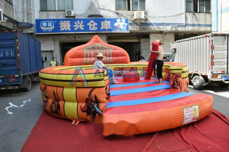 Arena de gladiadores inflable con dos jugadores duelando sobre pedestales acolchados