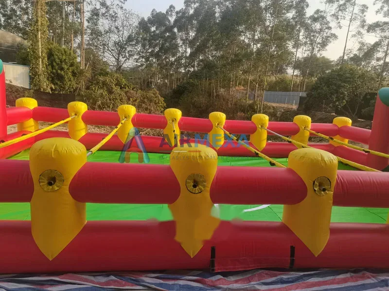 Cancha de futbolito humano inflable con jugadores sujetos a barras en evento
