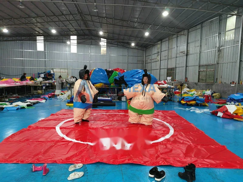 Dos personas con trajes de sumo inflables compitiendo sobre tapete acolchado